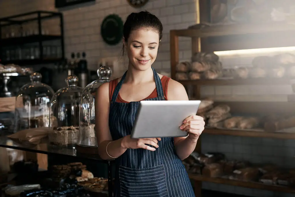 Empreendedora olhando um tablet em uma cafeteria