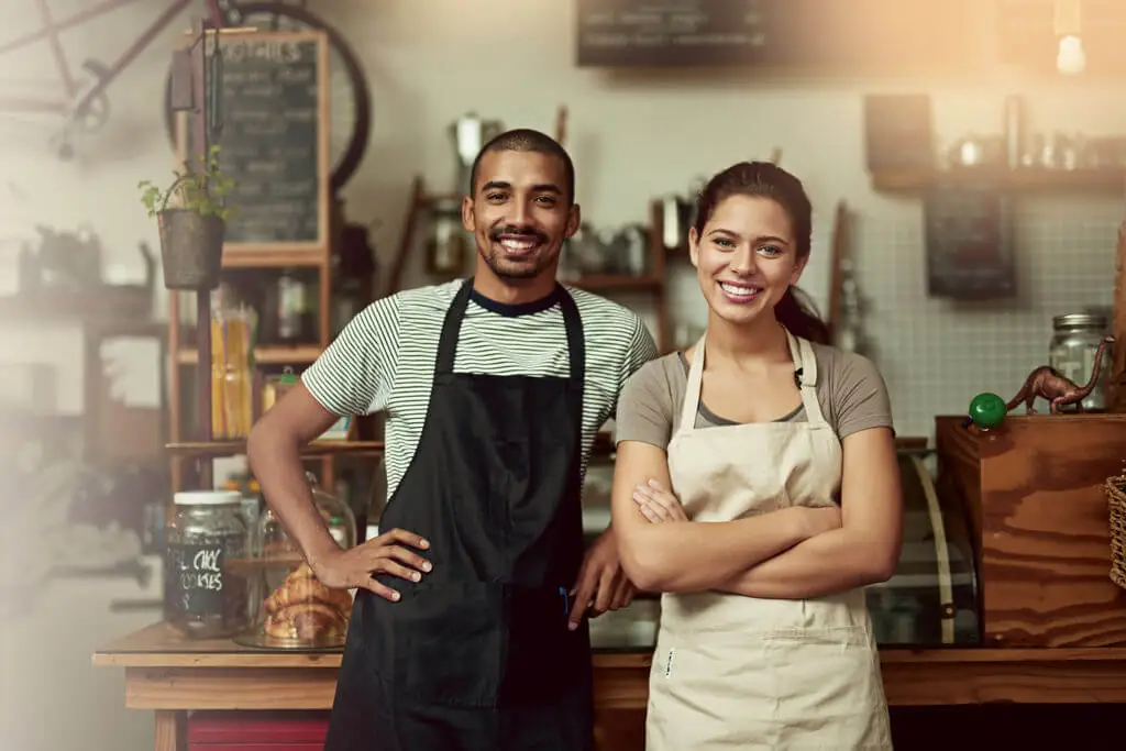 Casal de empreendedores sorrindo em seu estabelecimento