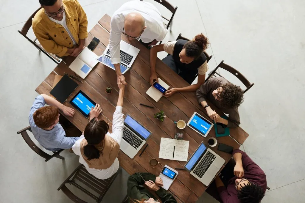 Equipe reunida em volta de uma mesa de trabalho com notebooks