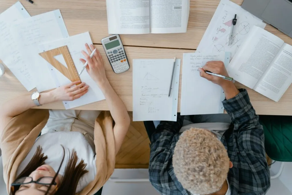 Pessoas estudando e fazendo cálculos sobre uma mesa